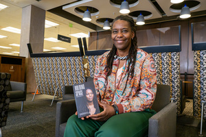 Aminata Cairo poses with her book, “Holding Space.” In the book, she presents a more “accessible” approach to topics of diversity and inclusion.
